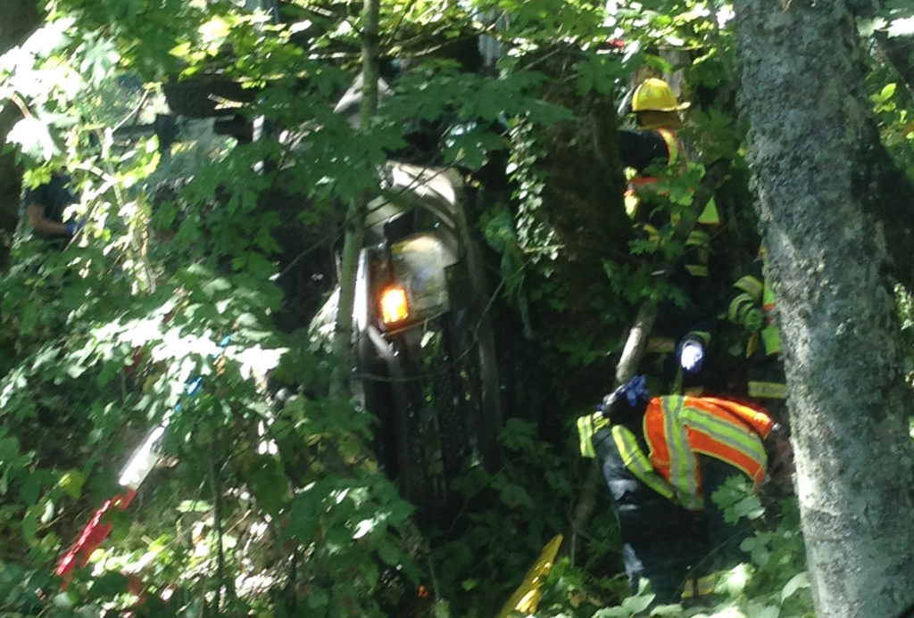 Crews work to free a driver from a pickup that went off eastbound state Highway 14 west of Camas on Saturday and ended up wedged in trees on a steep embankment.