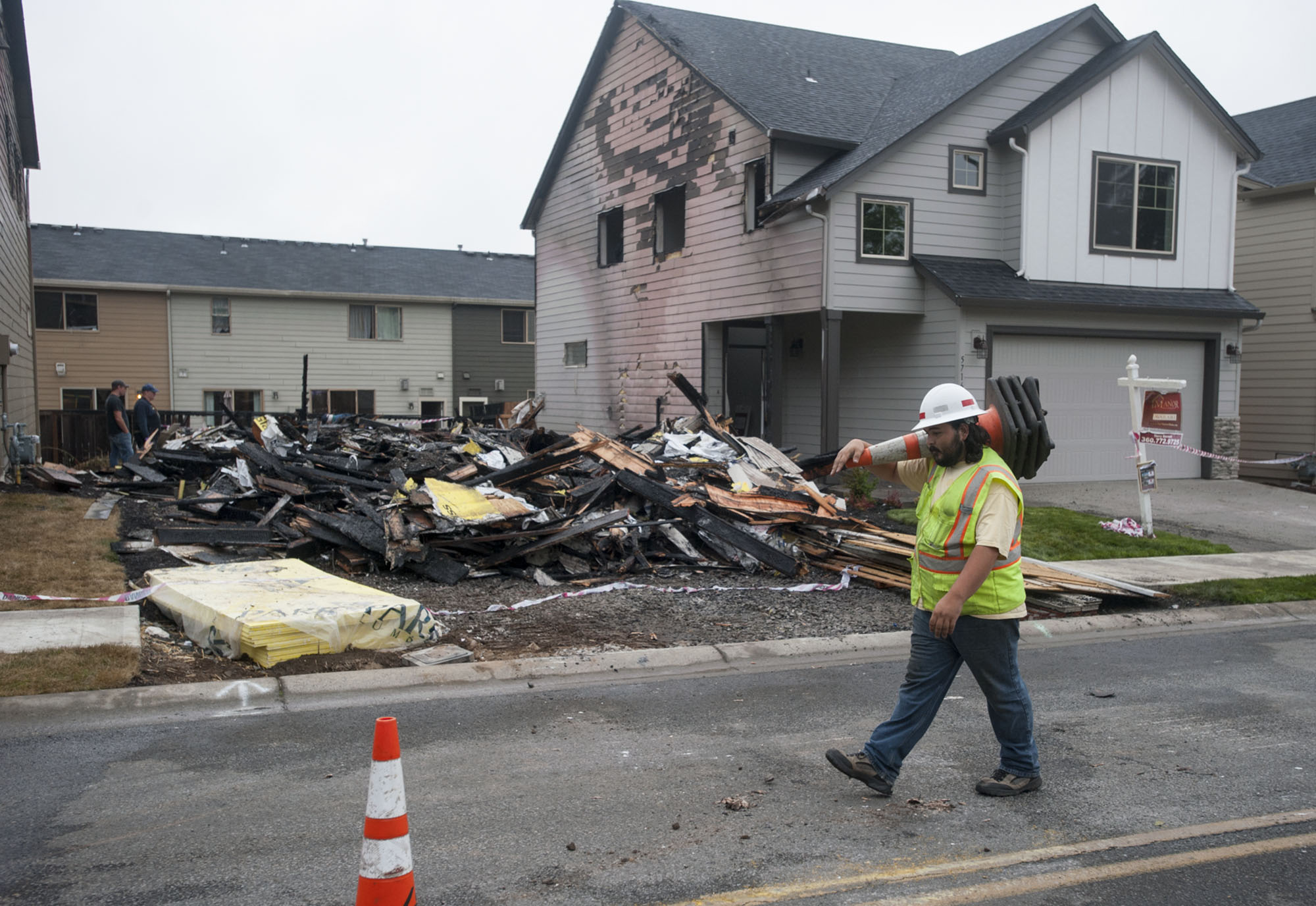 Matthew Zugajewicz of Northwest Traffic Control prepares to set up cones to route traffic around the scene of a fire at a construction site Thursday morning. The fire was reported at about 1:30 a.m. in the 5700 block of Northeast 47th Street.