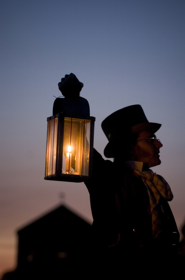 A re-enactor raises a lantern during an evening tour at Fort Vancouver National Historic Site.