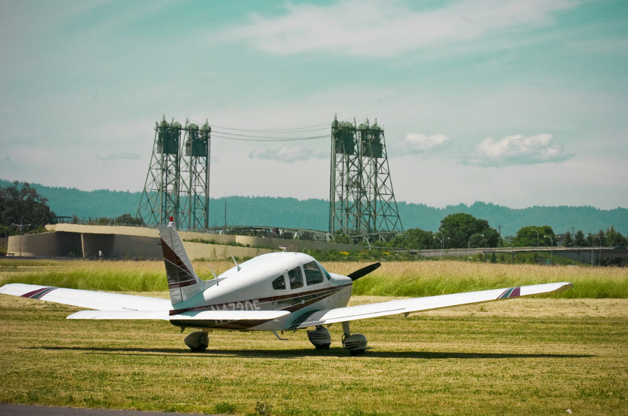 A plane sits at Pearson Field with the Interstate 5 Bridge in the background.