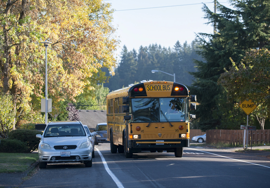 A school bus drives past parked cars along Northeast 81st Avenue on Sept. 28. Some residents say the lack of sidewalks is a danger for students of Peter S. Ogden Elementary school at the end of the street.