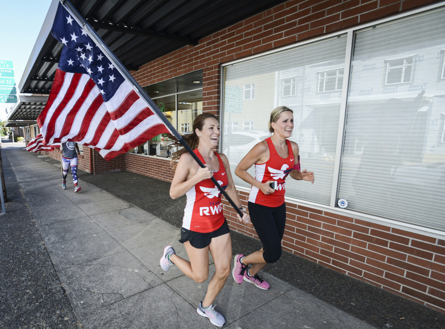 Marcelle Abel, holding the flag, and Lyndsey Lanphere run Tuesday morning down Columbia Street in Vancouver to the entrance of the Clark County Veterans Assistance Center, completing their leg in the Old Glory Relay.
