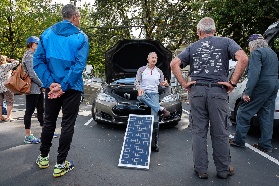 John Patterson, former owner of Mr. Sun Solar, in center, talks with attendees Sunday afternoon at an electric car gathering at Clark Public Utilities in Vancouver. Some electric car owners power their vehicles using solar energy.