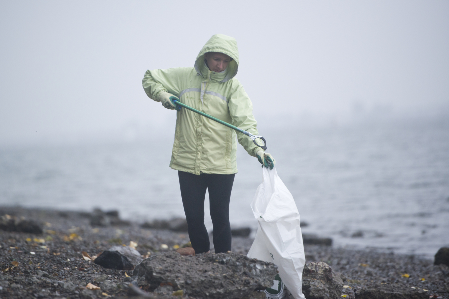 Christina Hubbard of Vancouver drops trash into a bag during a waterfront cleanup event Saturday morning along the Columbia River Waterfront Renaissance Trail in Vancouver. The effort was organized by SOLVE Oregon and the Fort Vancouver National Historic Site.