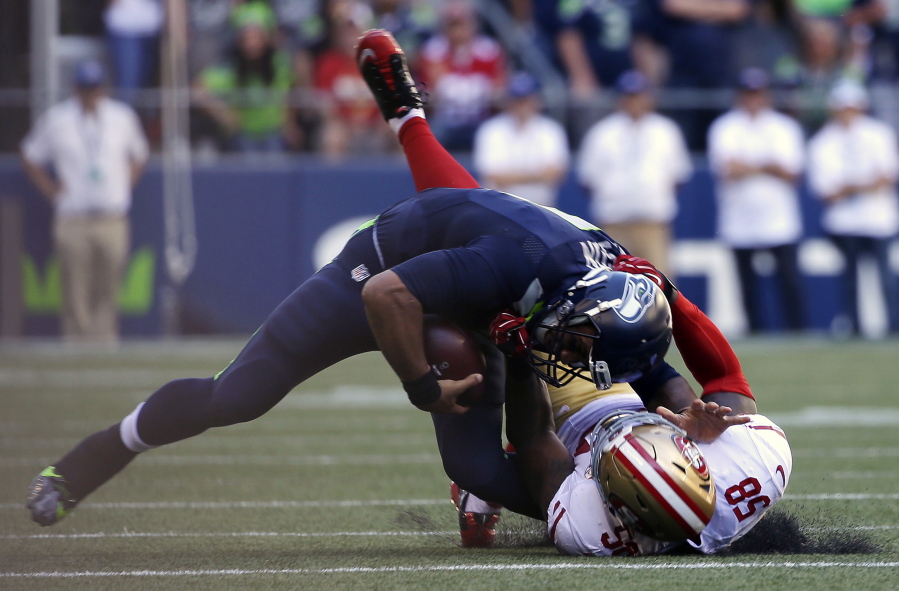 Seattle Seahawks quarterback Russell Wilson, top, is pulled down by San Francisco 49ers&#039; Eli Harold in the second half of an NFL football game, Sunday, Sept. 25, 2016, in Seattle. (AP Photo/Ted S.