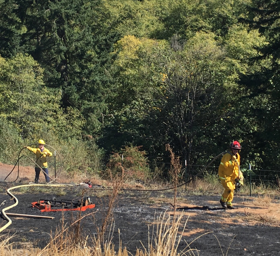 Firefighters tend to a roughly 1-acre field fire Tuesday near Woodland.