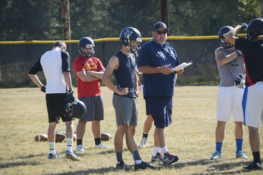 Quarterback Canon Racanelli, center, goes over a play with his dad, quarterback coach Josh Racanelli, during practice at Hockinson High School, Tuesday August 30, 2016.
