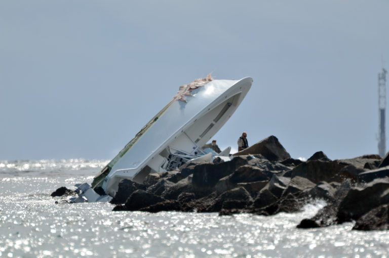 Investigators look at a boat overturned on a jetty, Sunday, Sept. 25, 2016, off Miami Beach, Fla. Authorities said that Miami Marlins starting pitcher Jose Fernandez was one of three people killed in the boat crash early Sunday morning. Fernandez was 24.