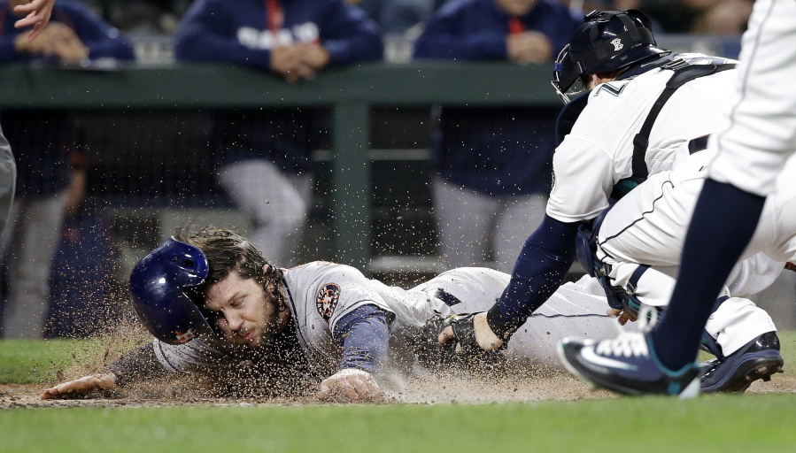 Houston Astros&#039; Jake Marisnick, left, loses his helmet as he scores while Seattle Mariners catcher Mike Zunino tags him during the fourth inning of a baseball game Friday, Sept. 16, 2016, in Seattle.