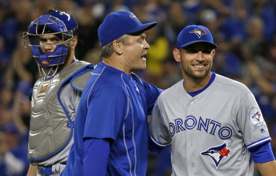 Toronto Blue Jays manager John Gibbons, center, smiles as he talks to starting pitcher Marco Estrada, right, after pulling him in the eighth inning of a baseball game against the Seattle Mariners as catcher Russell Martin looks on at left, Monday, Sept. 19, 2016, in Seattle. (AP Photo/Ted S.