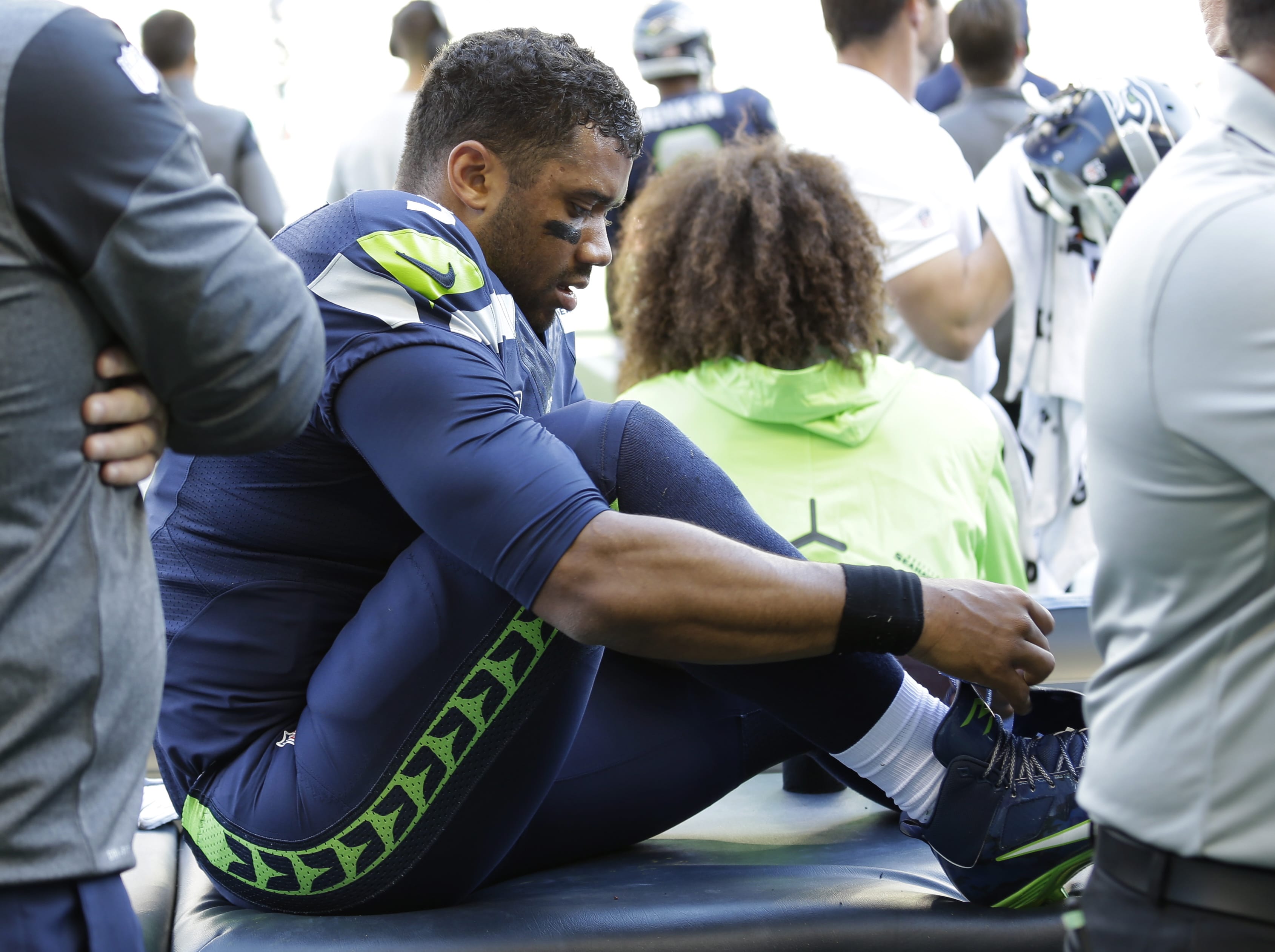Seattle Seahawks quarterback Russell Wilson laces his shoe after getting his ankle taped following a play during the second half of an NFL football game against the Miami Dolphins, Sunday, Sept. 11, 2016, in Seattle.