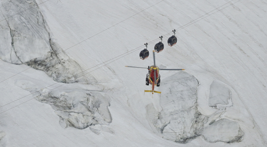 An EC-135 helicopter hovers Friday near the Mont Blanc cable car line that stalled Thursday afternoon after its cables reportedly tangled, stranding tourists in midair.