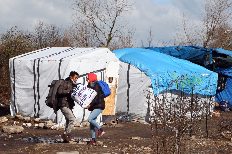 Unidentified migrants leave the makeshift camp near Calais, France, on March 3, 2016.