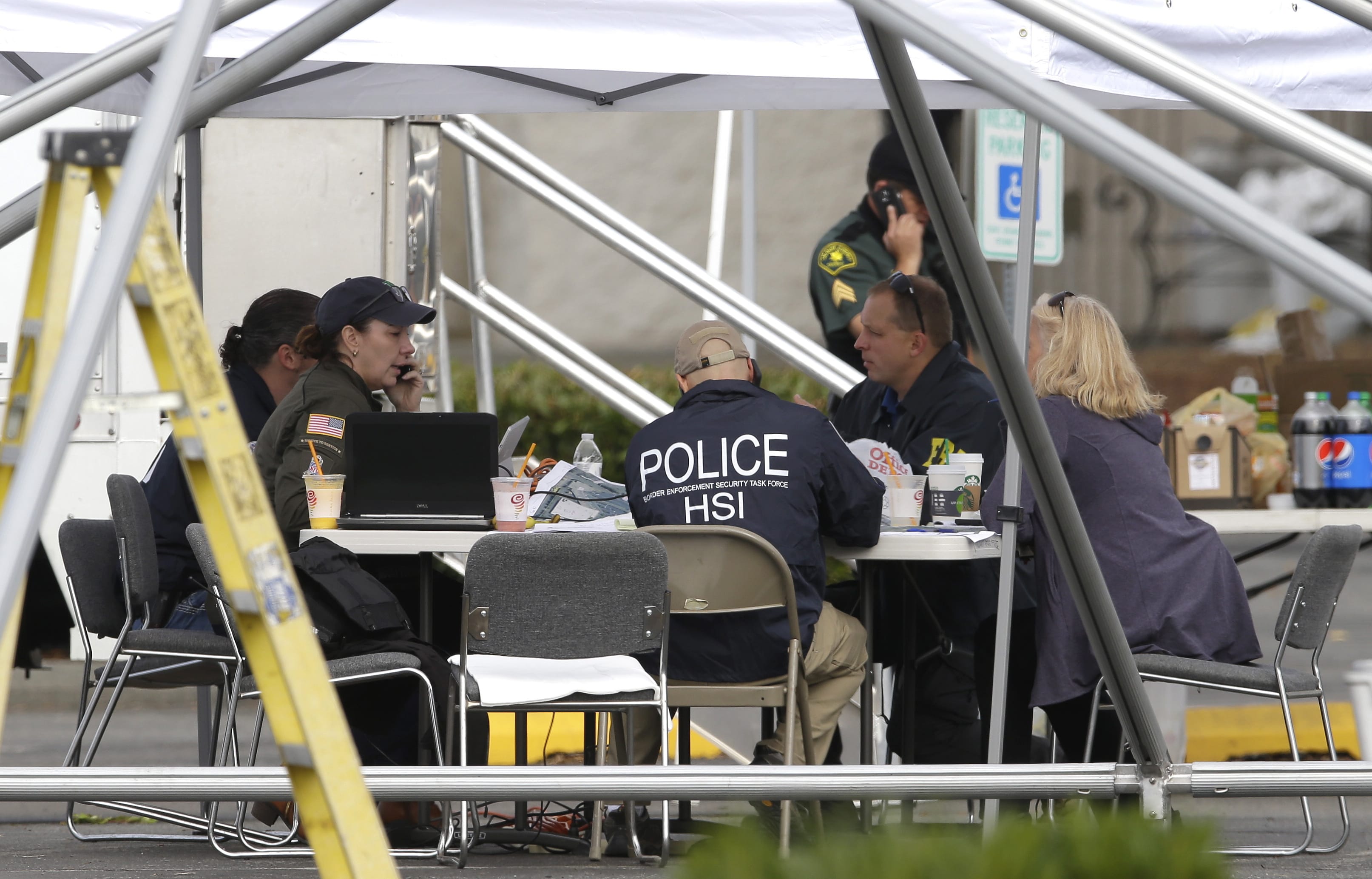 Law enforcement officials work under a tent, Saturday, Sept. 24, 2016, outside the Cascade Mall in Burlington, Wash.  Authorities said Saturday several people were dead after the shooting Friday night and the suspect was still at large. The identity of the suspect, his motive and how he got a rifle into the mall remained unanswered. (AP Photo/Ted S.