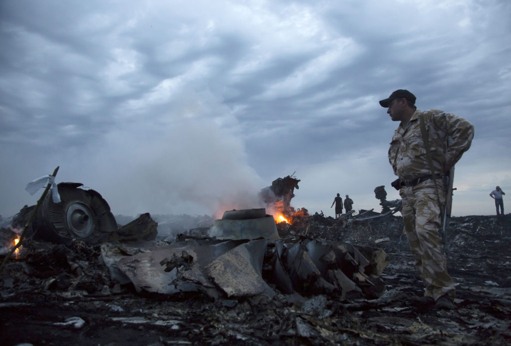 FILE - In this Thursday, July 17, 2014 file photo, people walk amongst the debris, at the crash site of a passenger plane near the village of Grabovo, Ukraine. Relatives of victims of the shooting-down of a Malaysia Airlines jetliner over Ukraine more than two years ago were gathering Wednesday, Sept. 28, 2016 to learn the preliminary results of a Dutch-led criminal probe of the disaster that claimed 298 lives.