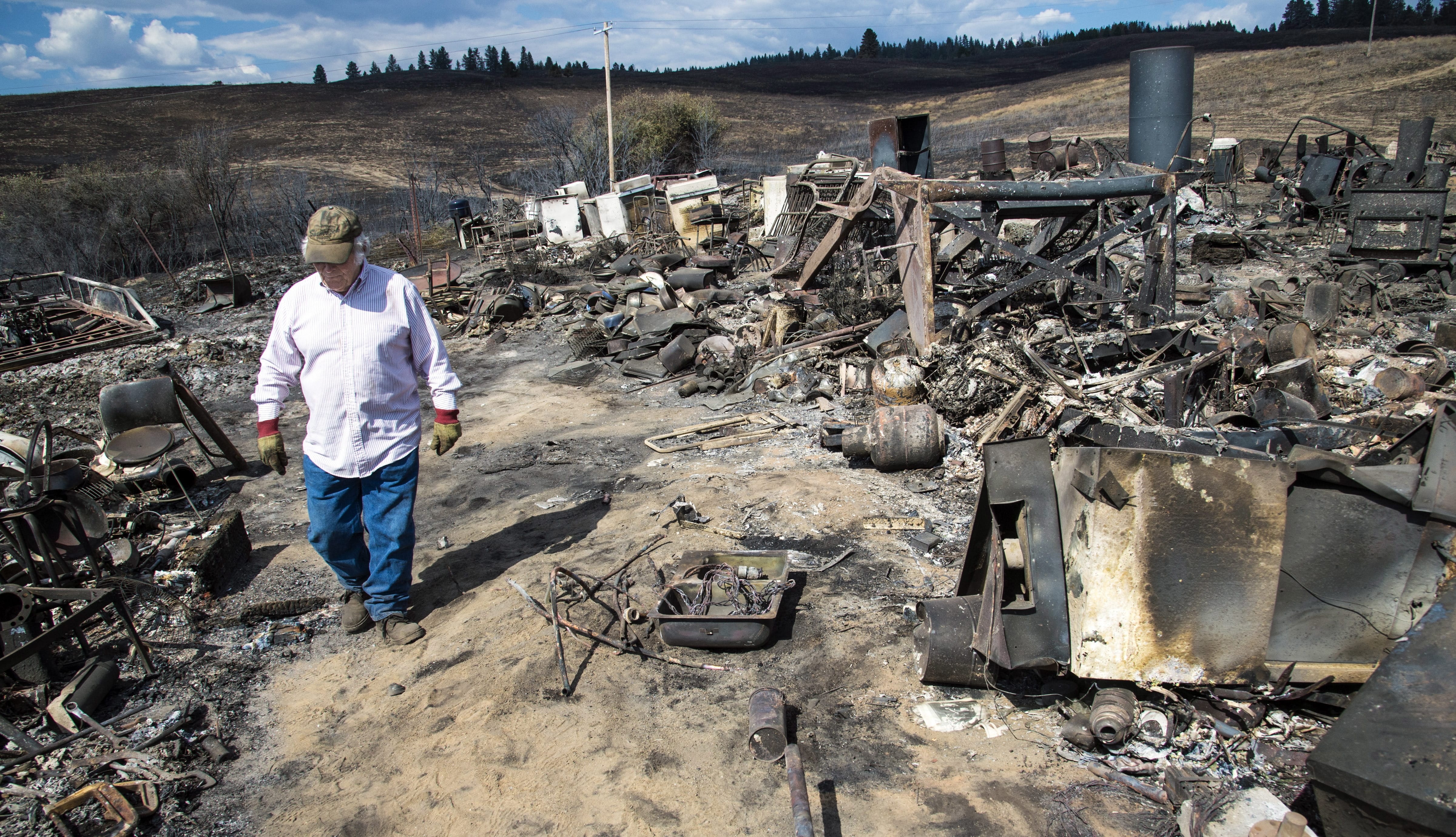 FILE -- In this Aug. 25, 2016, file photo, Vern Scherrer, 83, walks through the burned remains of his rental property near Wellpinit, Wash. After two consecutive years in which wildfires set acreage records in Washington state, this fire season has been very light. In fact, wildfires were smaller and less destructive in Washington, Oregon and Idaho this year, thanks to a heavy winter snowpack and some rain in the spring and summer months.