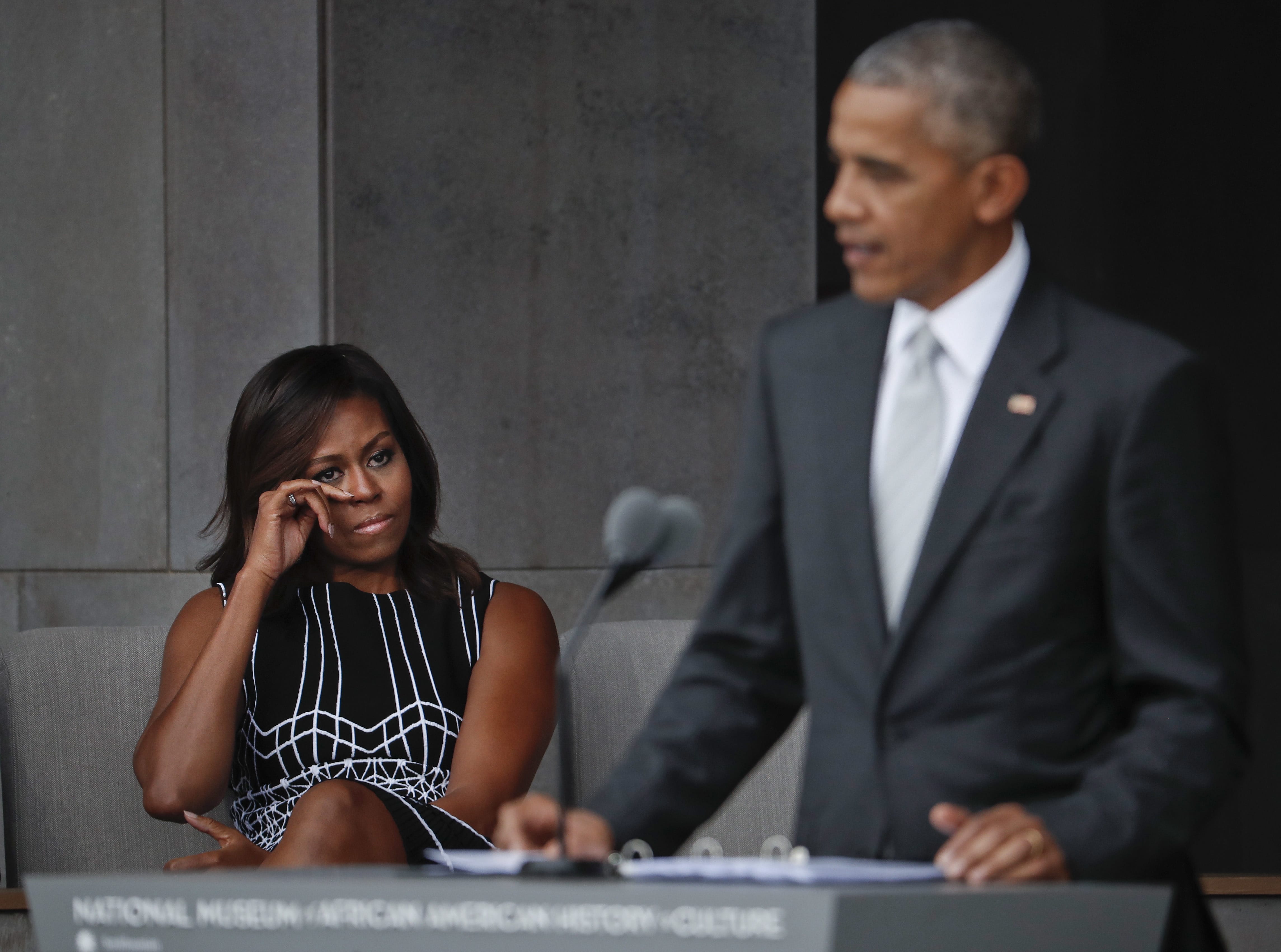 First lady Michelle Obama wipes her eyes as she listens to her husband, President Barack Obama, speak at the dedication ceremony for the Smithsonian Museum of African American History and Culture on the National Mall in Washington, Saturday, Sept. 24, 2016.
