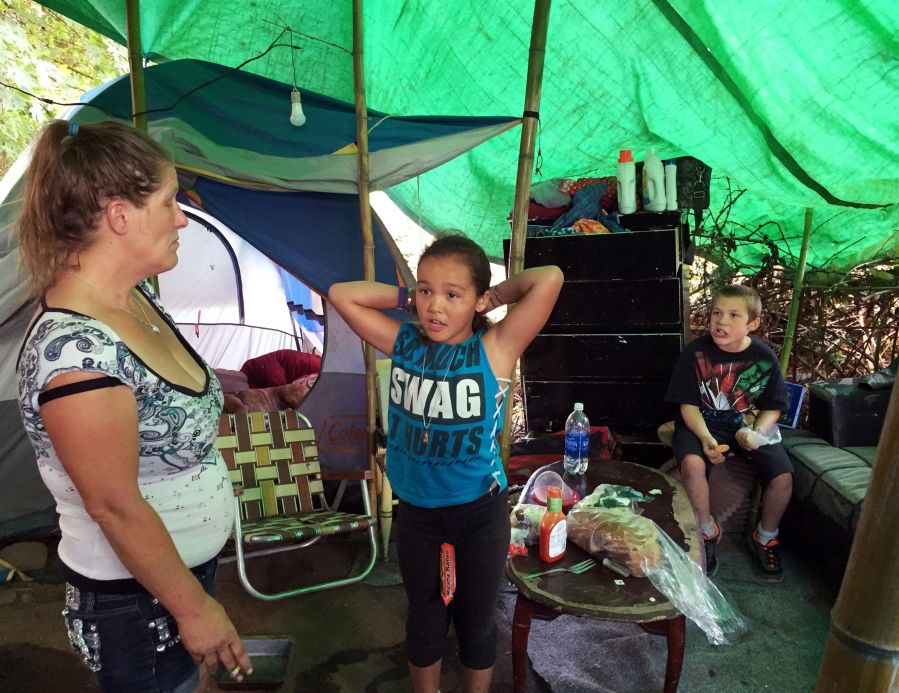 Deitra Schmer watches as her granddaughter, Andrea Brown, brushes her hair and grandson Adrian Atkinson, right, looks on in Schmer&#039;s tent in a homeless encampment along the Springwater Corridor bike and pedestrian trail in Portland in August.