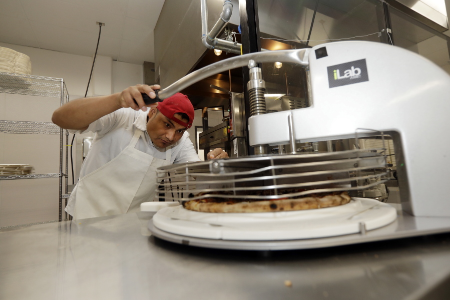 Noel Lopez, at left, slices a pizza at Zume Pizza in Mountain View, Calif.