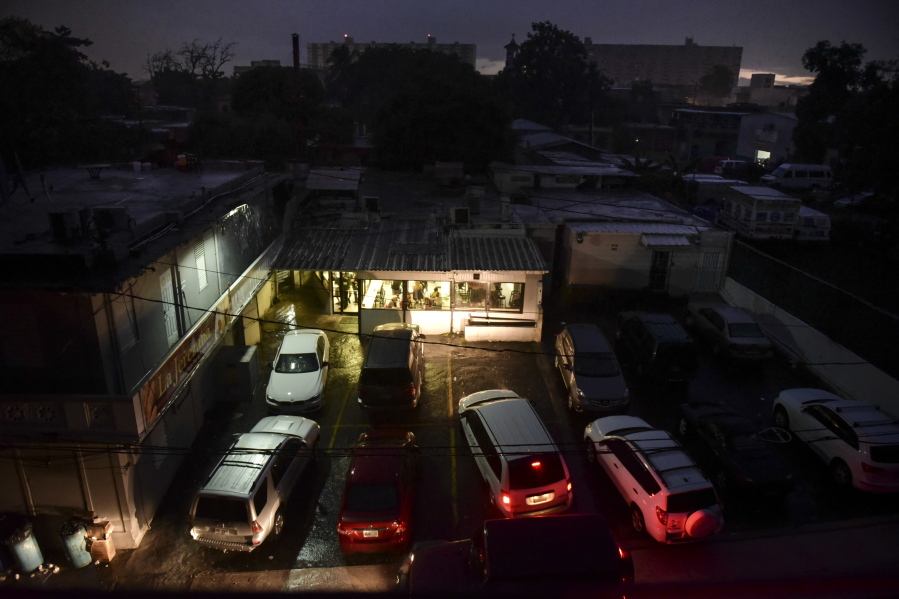 Motorists illuminate a storefront with their headlights as they drive in to buy bread after a massive blackout Thursday in San Juan, Puerto Rico.