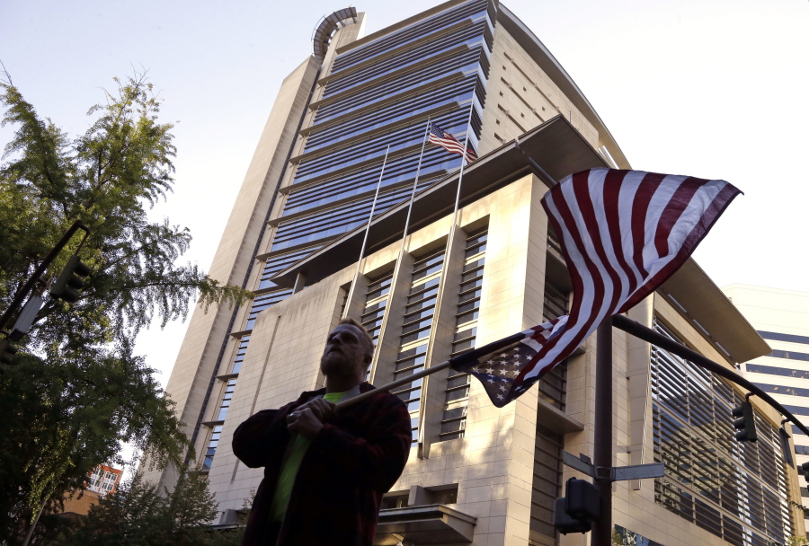 A protestor, who would only identify himself as Robert, flies an upside down American flag Tuesday outside the federal courthouse in Portland.
