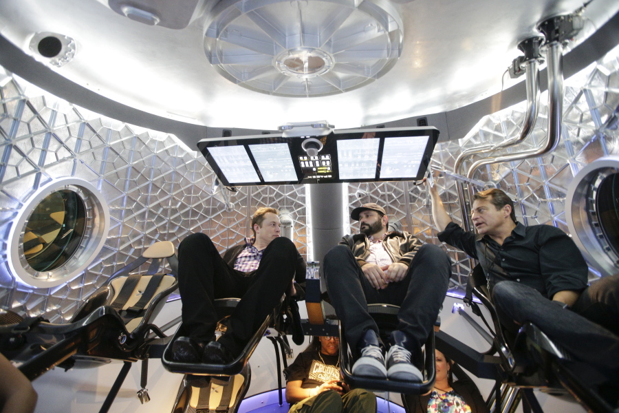 Elon Musk, left, CEO and CTO of SpaceX, talks with guests May 29, 2014, inside a mockup of the SpaceX Dragon V2 spacecraft at the headquarters in Hawthorne, Calif. The capsule was named for &quot;Puff the Magic Dragon,&quot; a jab at those who scoffed when Musk founded the company in 2002 and set the space bar exceedingly high. (Jae C.