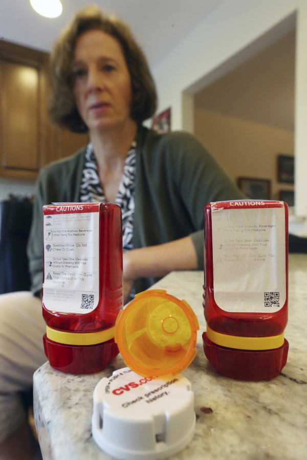 Shelley Ewalt sits in her home, in Princeton, N.J., near an open amber-colored CVS pharmacy prescription bottle and two uniquely designed red ones from Target.