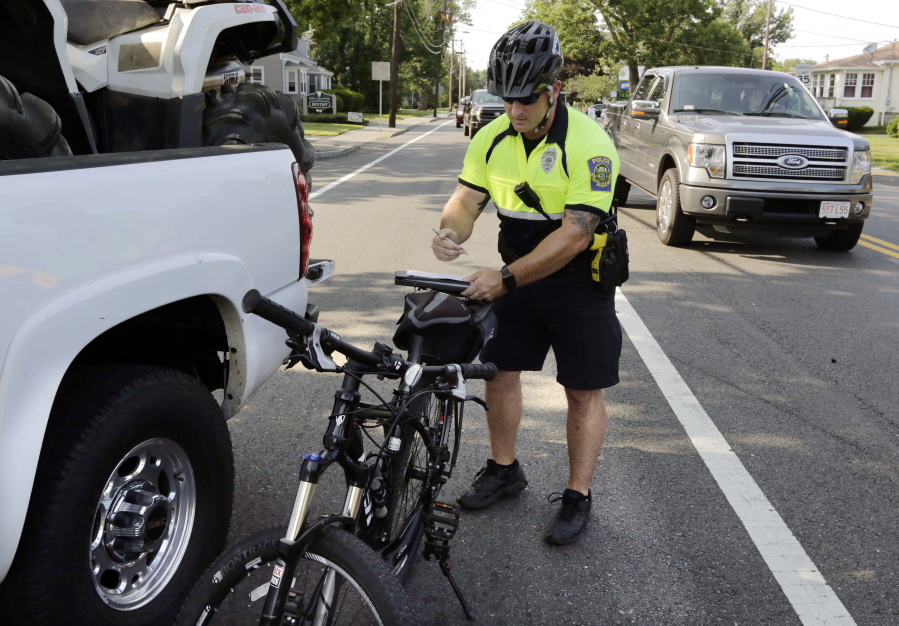 West Bridgewater, Mass., Police Officer Matthew Monteiro writes a texting-while-driving citation for a motorist on July 20. He pulled the vehicle over while patrolling on his bicycle.