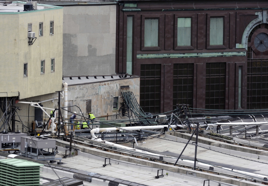 Workers examine a section of the roof at the Hoboken station where a train crashed into the building, Thursday Sept. 29, 2016 in Hoboken, N.J. A rush-hour commuter train crashed through a barrier at the busy Hoboken station and lurched across the waiting area Thursday morning, killing one person and injuring more than 100 others in a tangle of broken concrete, twisted metal and dangling wires.