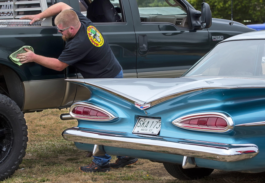 Gordon Moore polishes his Ford F-250 truck next to a Chevy in Longview last month for the Unique Tin Car Show and Cruise.