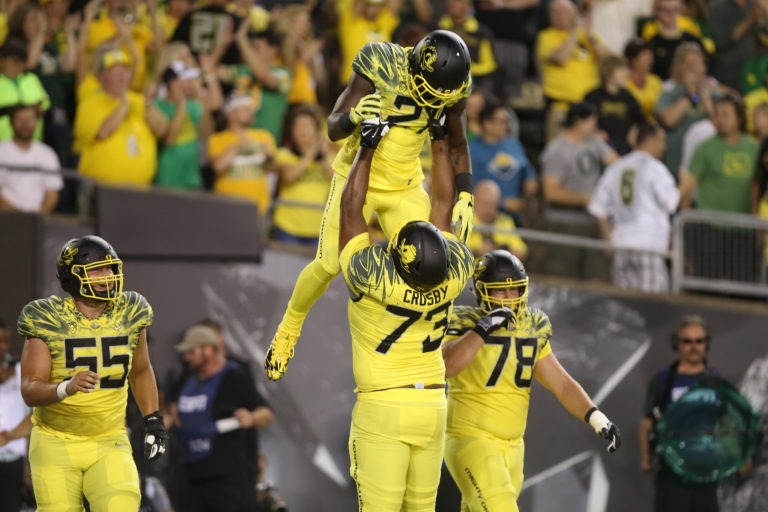 Oregon's Royce Freeman, center, is hoisted in the air by teammate Tyrell Crosby after scoring a touchdown against Virginia during the first quarter of an NCAA college football game Saturday, Sept. 10, 2016 in Eugene, Ore.
