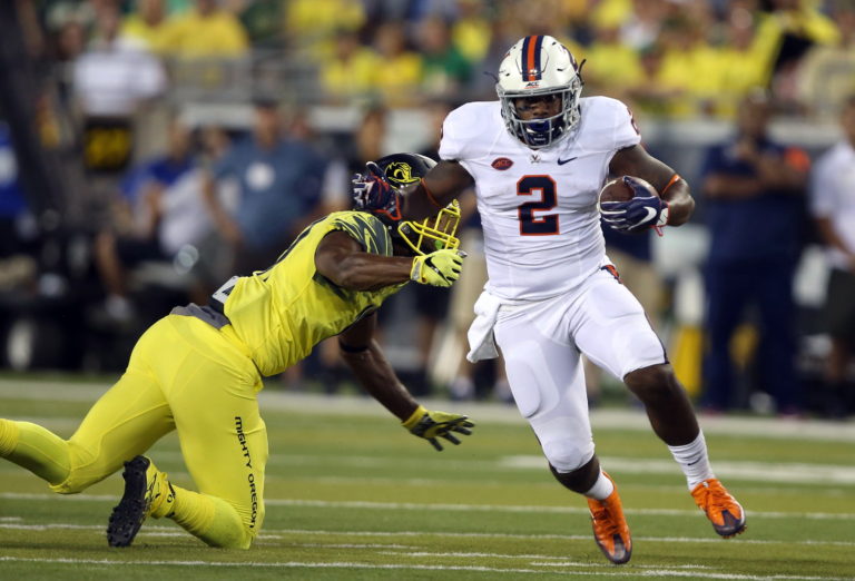 Virginia tailback Albert Reid, right, escape the grasp of Oregon's Justin Hollins, left, during the first quarter of an NCAA college football game Saturday, Sept. 10, 2016 in Eugene, Ore.