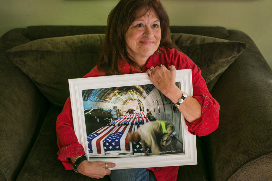 Tami Silicio poses with the photograph she made as an air cargo worker in 2004 that shows flag-draped coffins being transported back to the United States on Friday, Oct. 21, 2016, in Seattle. The image was recently named one of the most influential photographs of all time by Time magazine.
