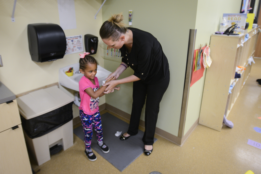 Ashley Horn helps her daughter, Icess, 4, dry her hands at Hough Early Learning Center in Vancouver on Thursday. Horn, a single mother, credits the Hough Early Learning Center for helping her find a job, get her GED and enroll in cosmetology school.