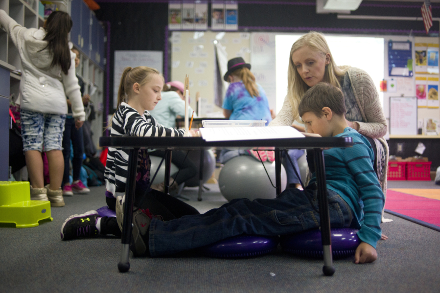 Megan Lascik helps Trevor Maxwell, 8, on an assignment Tuesday while Trevor sits on core discs, one of the multiple flexible seating options in Lascik&#039;s third-grade class at Woodland Intermediate School.