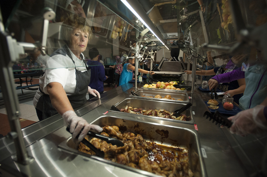Kitchen manager Connie Lane, left, helps students load up their plates with chicken and other items made from local ingredients during a special lunch in honor of Taste Washington Day at Union Ridge Elementary School.