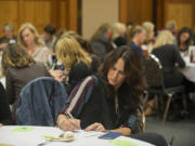 Janna Moats writes a check Monday to nonprofit Friends of the Children during the first meeting of 100 Women Who Care of SW Washington at The Heathman Lodge in Vancouver.