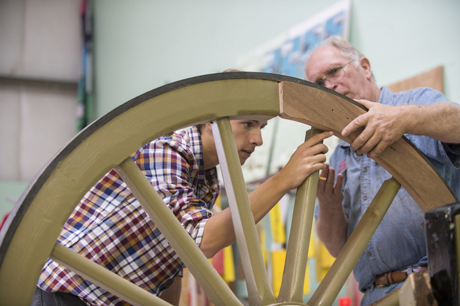 John Keller, 17, left, and historical preservation specialist Fred Munhoven check out the fit of a component known as a felloe in a cannon wheel last week.