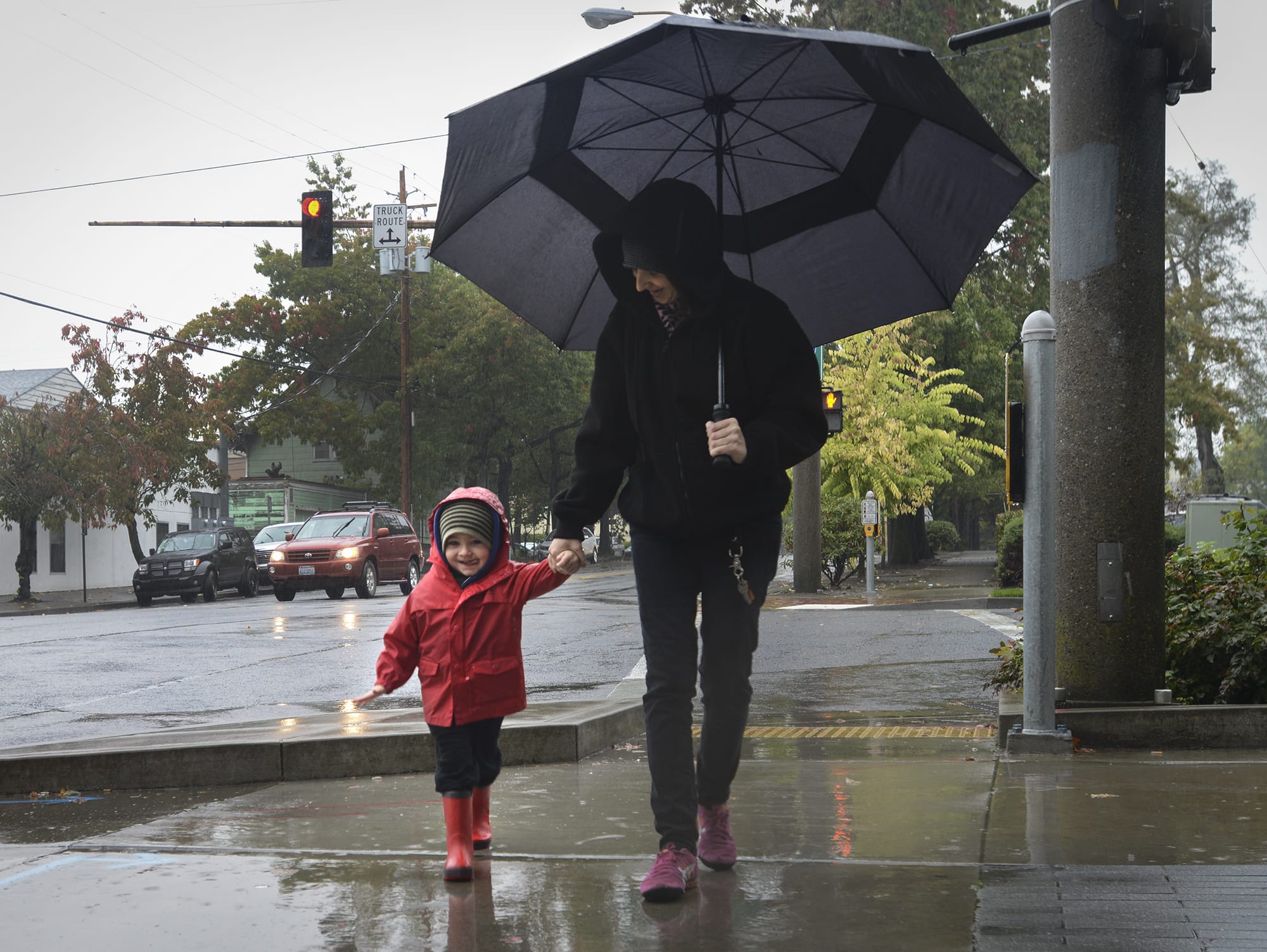 Ethan Parker, 3, and Suzanne Mark, right, try to keep dry while walking to the Vancouver Public Library in the rain on Thursday.