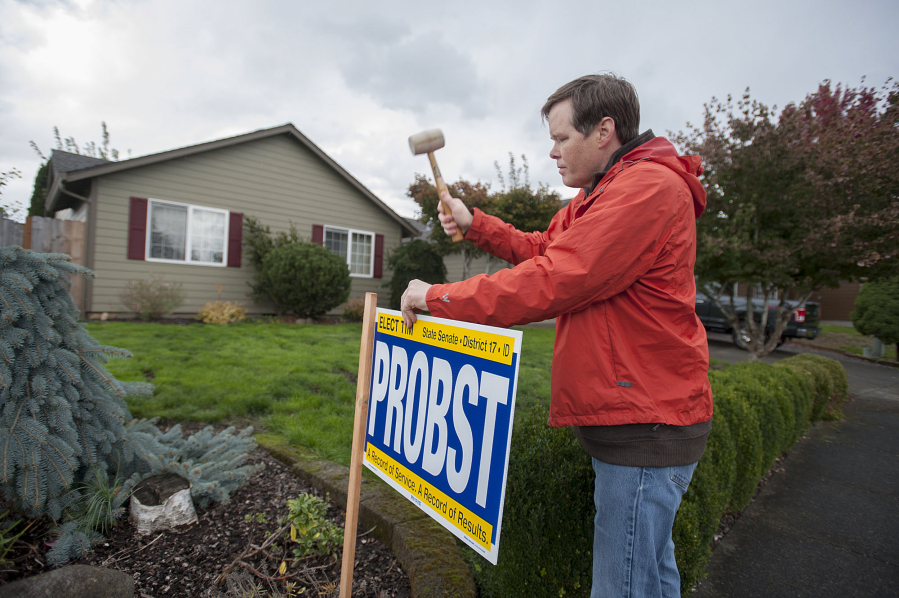 Democratic state Senate candidate Tim Probst sets up a lawn sign outside the home of a voter in northeast Vancouver on Friday.