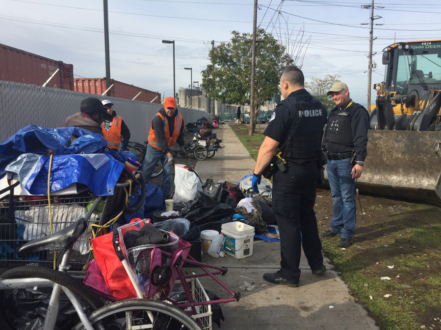 Vancouver Police Department officers and Vancouver Public Works employees help people clean up their belongings Wednesday near Share House in west Vancouver.
