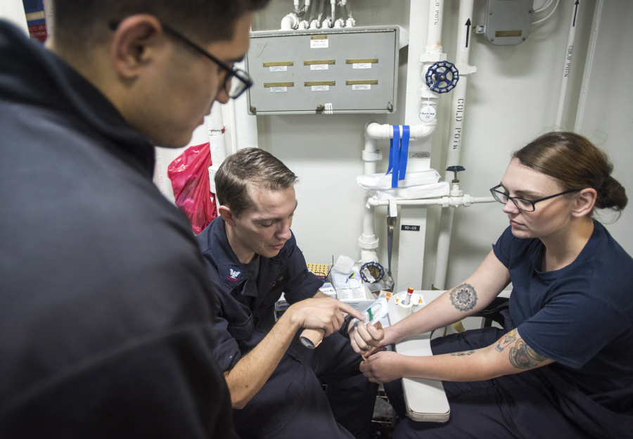 Central Vancouver: Petty Officer 2nd Class Evan Fitch, center, of Vancouver teaches blood-drawing techniques to Petty Officer 3rd Class Martin Salinas, left, while aboard the USS Bonhomme Richard, which is operating in the South China Sea.