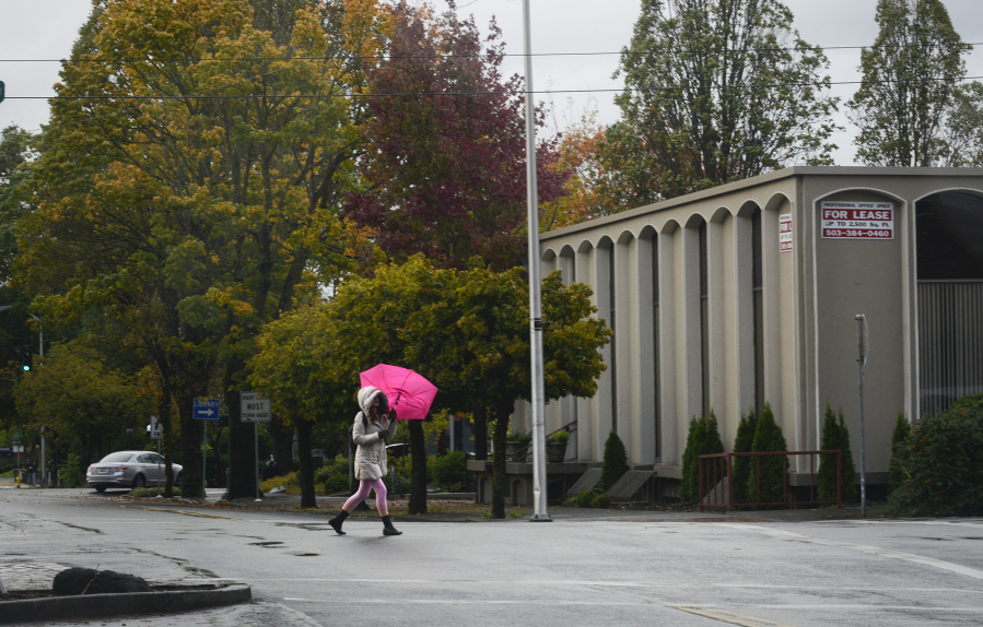 A woman tries to stay dry while crossing Main Street in downtown Vancouver.