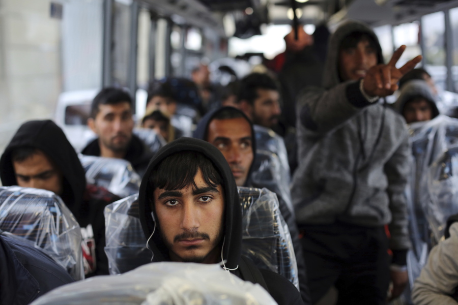 Migrants sit on a bus going to Normandy on Monday as they leave the makeshift migrant camp known as &quot;the jungle&quot; near Calais, northern France. French authorities are beginning a complex operation to shut down the camp.