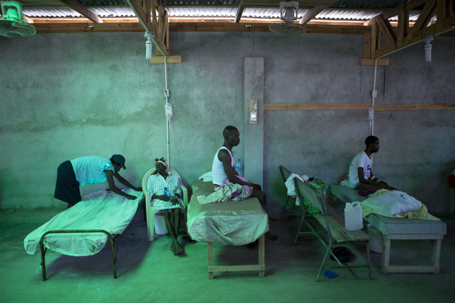 The daughter of 84-year-old Armant Germain replaces the sheets on her bed, in the cholera ward at a hospital in Les Cayes Haiti, on Tuesday. Health authorities have warned that Hurricane Matthew has created conditions that are likely to cause an increase in the deadly waterborne cholera virus.