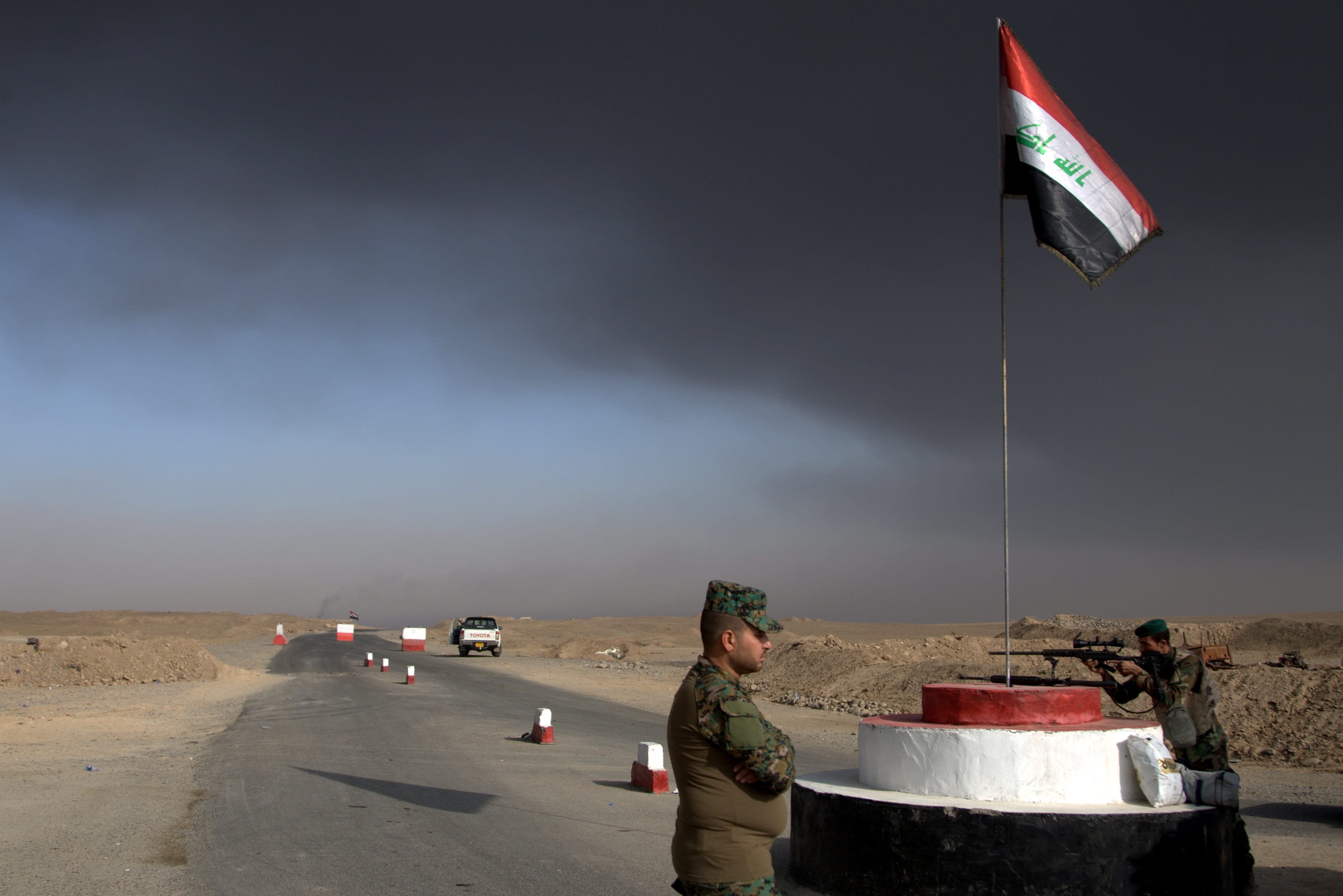 Iraqi troops guards a checkpoint near the village of Awsaja, Iraq, as smoke from fires lit by Islamic State militants at oil wells and a sulfur plant fills the air on Saturday, Oct. 22, 2016. U.S. military officials say that a fire at the sulfur plant in northern Iraq is creating a potential breathing hazard for American forces and other troops at a logistical base south of Mosul.