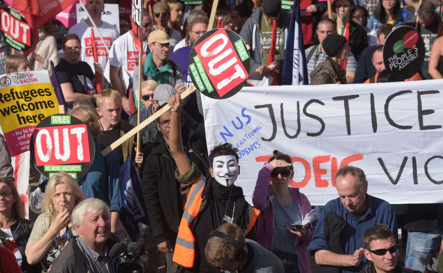 Protesters brandish various placards and signs as they gather at an anti-austerity demonstration outside the Conservative Party Conference in Birmingham, England, on Sunday.  The ruling Conservative Party is holding its annual party conference in Birmingham, and Prime Minister Theresa May is scheduled to give a key note speech to conference Sunday.
