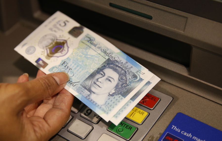 A member of staff at a branch of Halifax bank, in London, displays a new British 5 pound sterling note, made of plastic, which is being launched Tuesday.  The beleaguered British pound plummeted briefly to a fresh 31-year low Friday, amid intensifying concerns about Britain&#039;s exit from the European Union.