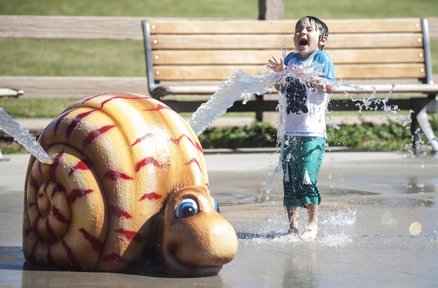 A boy gets squirted by a snail-shaped water feature Thursday at Stanton Central Park in Stanton, Calif.