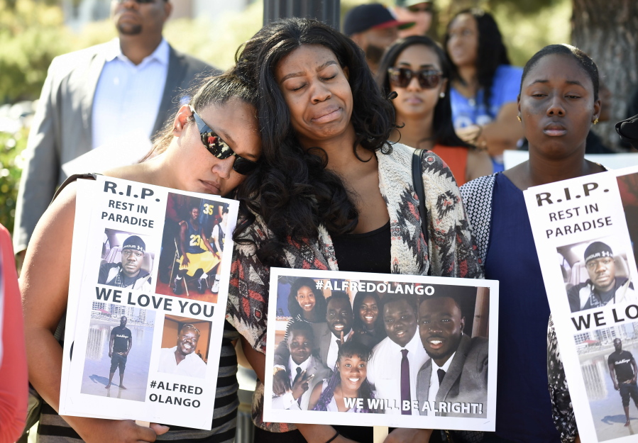Protesters hold signs in honor of Alfred Olango before a march in reaction to the fatal police shooting of the unarmed black man, in El Cajon, Calif., Saturday.  Olango, a Ugandan refugee, was shot by an El Cajon police officer on Tuesday.